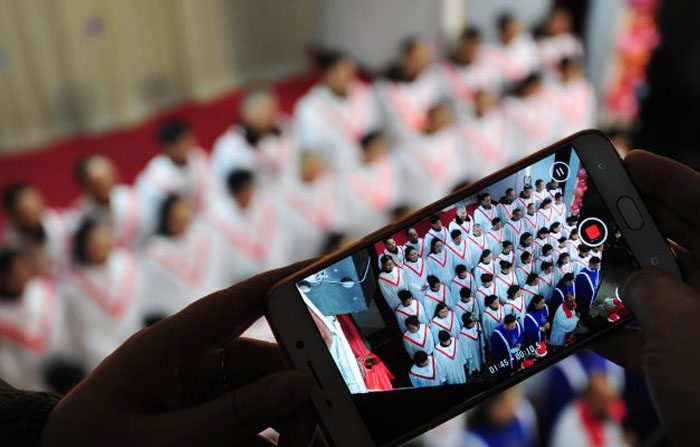 24 dicembre, Chiesa di Fuyang, provincia di Anhui. Durante la messa della veglia di Natale, un partecipante filma il coro. Segnalazioni da tutta la Cina, dimostrano che le celebrazioni dei cristiani cinesi per il Natale sono state represse fortemente dal regime (foto: Afp/Getty Images).
