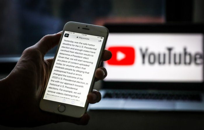 Sullo schermo del telefono il comunicato di YouTube che annuncia che l'azienda inizierà immediatamente a rimuovere i contenuti che parlano di «brogli» nelle elezioni presidenziali americane 2020. (Samira Bouaou/The Epoch Times).