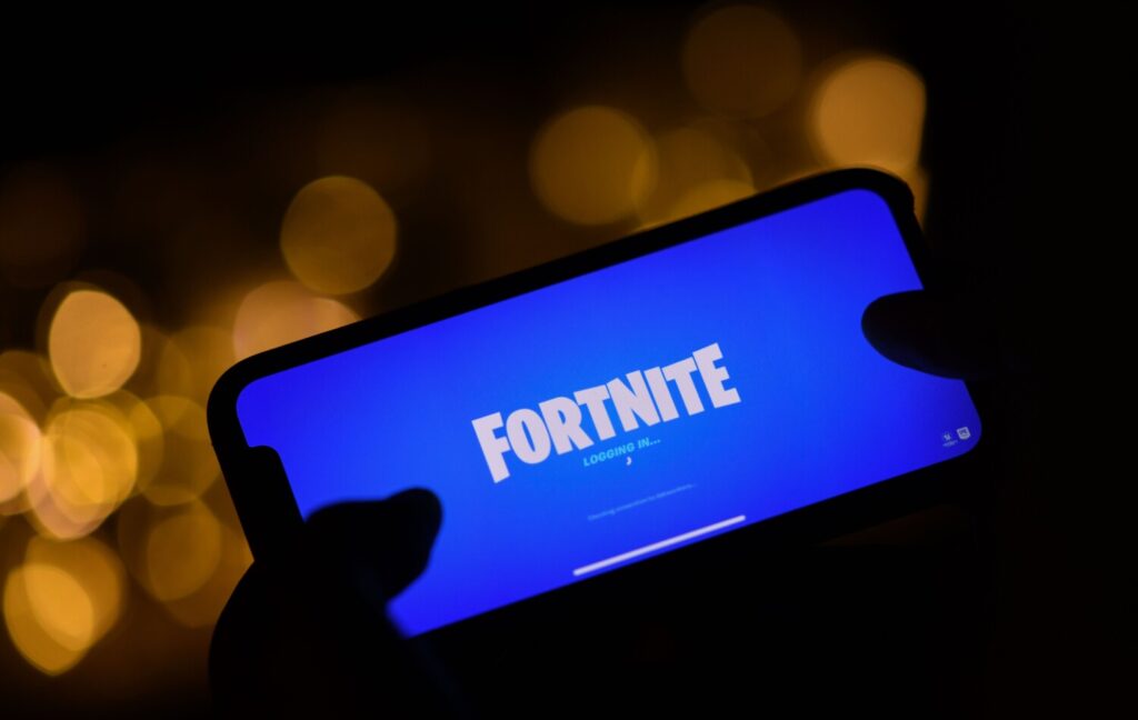 Questa immagine illustrativa mostra una persona che accede a ‘Fortnite’ di Epic Games, nel suo smartphone a Los Angeles, 14 agosto 2020. Il 13 agosto 2020 Apple e Google hanno ritirato il clamoroso Fortnite dai loro negozi di applicazioni mobili, dopo che il suo produttore, Epic Games, ha rilasciato degli aggiornamenti che eludono la condivisione dei guadagni con i colossi informatici. (Chris Delmas/AFP via Getty Images)