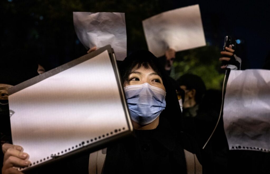 PECHINO, CINA - 27 NOVEMBRE: I manifestati tengono un pezzo di carta bianco, contro la censura, mentre marciano durante una protesta contro le severe misure restrittive ‘zero-COVID’, 27 novembre 2022, Pechino, Cina. I protestanti sono scesi per le strade in diverse città cinesi dopo che un incendio mortale di appartamento nella provincia dello Xinjiang ha suscitato indignazione nazionale mentre molti incolpano le restrizioni COVID per le morti (Kevin Frayer/Getty Images)