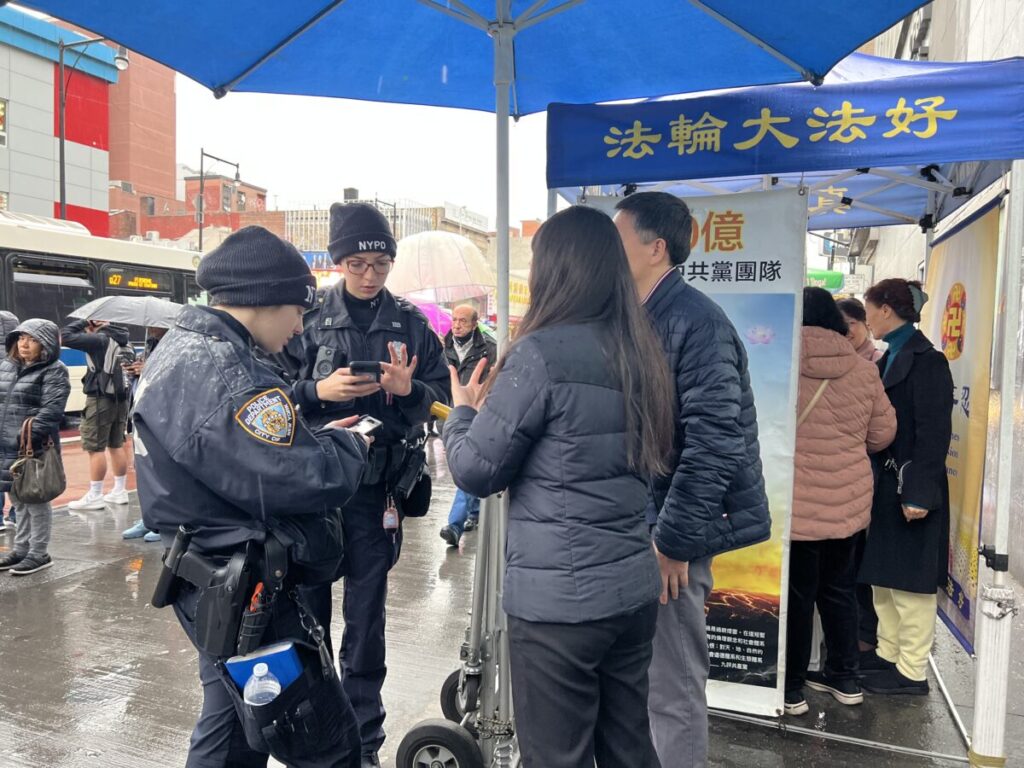 Gli agenti di polizia parlano con i praticanti del Falun Gong dopo che un uomo li ha aggrediti ad uno stand informazioni, nel quartiere Flushing del Queens, New York, 16 febbraio 2023. (Linda Lin/Epoch Times)