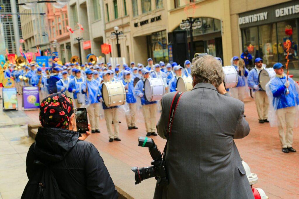 Le persone fotografano la Tianguo Marching Band mentre si esibisce a Ottawa il 3 maggio 2023, per celebrare la Giornata della Falun Dafa. (Jonathan Ren/The Epoch Times)