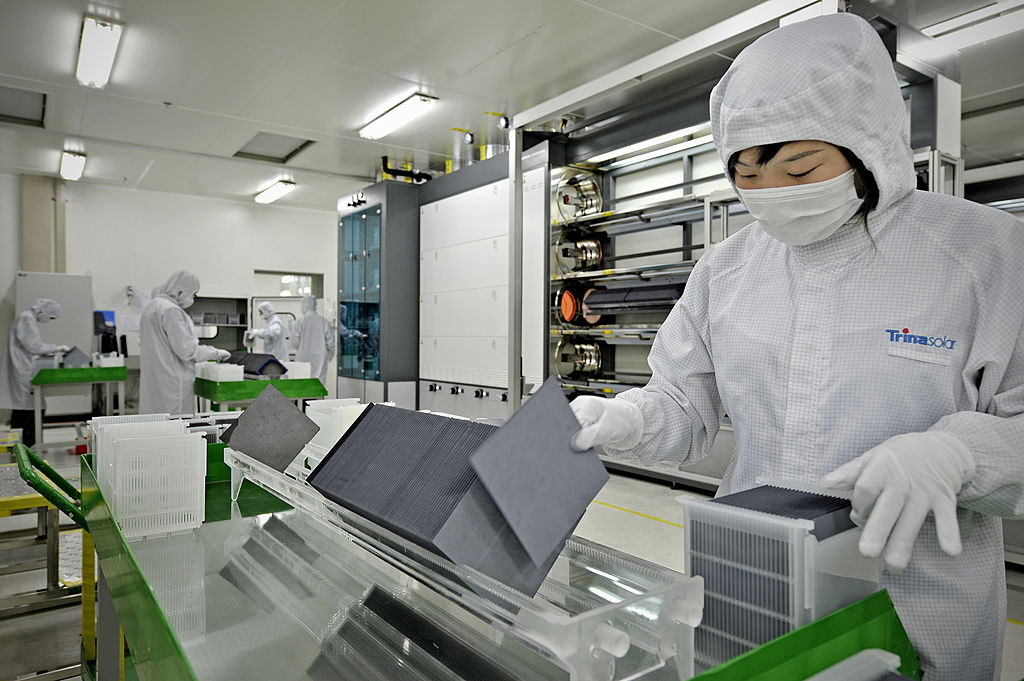 Un operaio mascherato in camice smista wafer di silicio nella fabbrica del produttore di celle solari Trina Solar a Changzhou, in Cina, il 28 novembre 2009. (PHILIPPE LOPEZ/AFP via Getty Images)