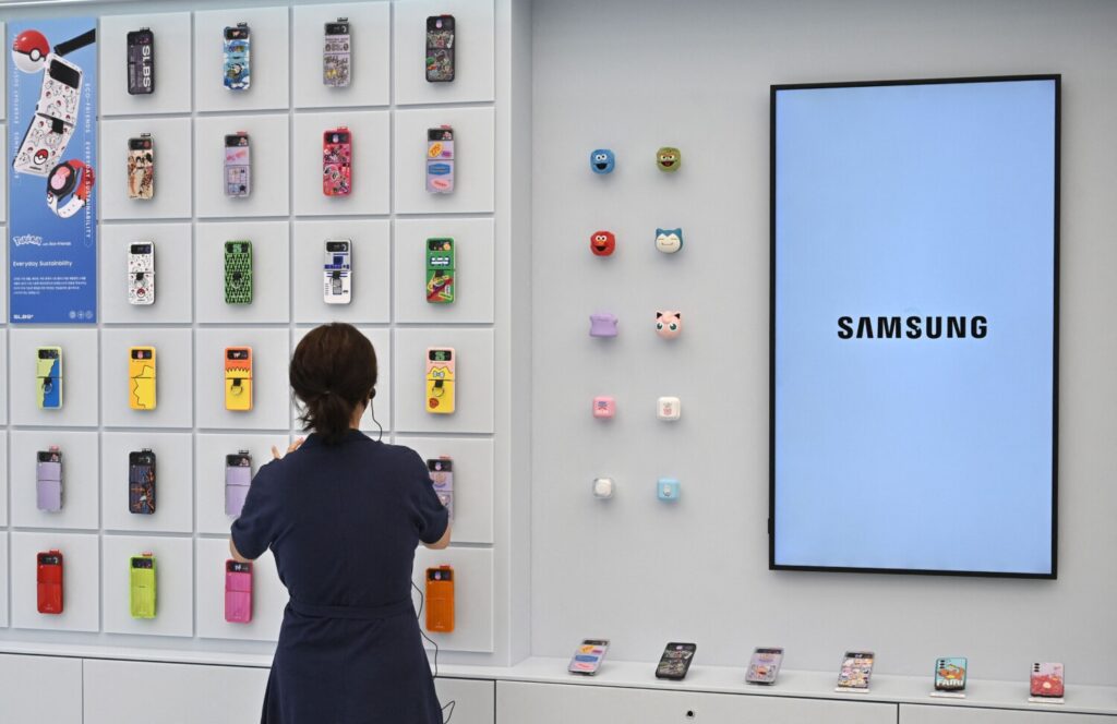 Una donna guarda gli accessori del Samsung Galaxy Z Flip4 esposti su una parete durante un evento di anteprima per i media del nuovo negozio principale di Samsung Electronics nel distretto di Gangnam a Seoul il 28 giugno 2023. (Jung Yeon-je/AFP via Getty Images)