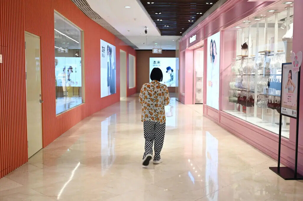 Una donna passa davanti ai negozi di un centro commerciale a Pechino il 18 luglio 2023. (Greg Baker/Afp via Getty Images)
