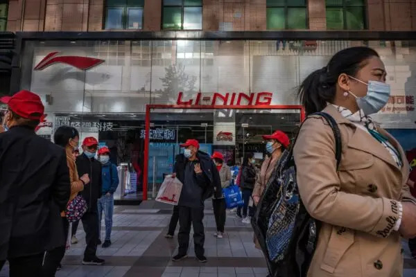 Turisti e consumatori passano davanti a un negozio Li-Ning, un marchio cinese di abbigliamento sportivo, in un quartiere commerciale di Pechino il 16 aprile 2021. (Kevin Frayer/Getty Images)
