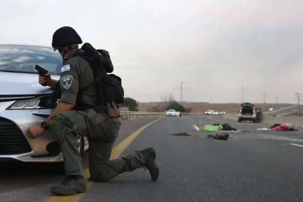 Un soldato israeliano si ripara dietro un'auto dopo che i terroristi di Hamas sono entrati a sud di Israele e hanno ucciso dei civili. Cadaveri israeliani sono visibili su una strada principale nei pressi del kibbutz israeliano Gevim, vicino al confine con Gaza, il 7 ottobre 2023. (Oren Ziv/Afp via Getty Images)