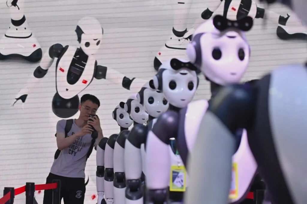 Un uomo fotografa dei robot durante la Conferenza mondiale sull'intelligenza artificiale (Waic) a Shanghai, il 7 luglio 2023. (Wang Zhao/Afp via Getty Images)