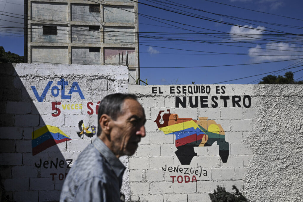 Un uomo cammina accanto a un murale che promuove un referendum per chiedere ai venezuelani di considerare l'annessione della regione di Essequibo, amministrata dalla Guyana, a Caracas, in Venezuela, il 28 novembre 2023. (FEDERICO PARRA/Afp via Getty Images)