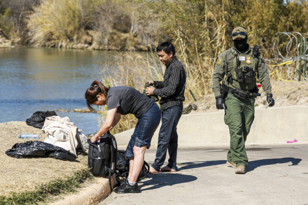 Un agente della polizia di frontiera arresta una coppia cinese che ha appena attraversato il Rio Grande dal Messico a Eagle Pass, in Texas, il 25 gennaio 2022. (Charlotte Cuthbertson/Epoch Times)
