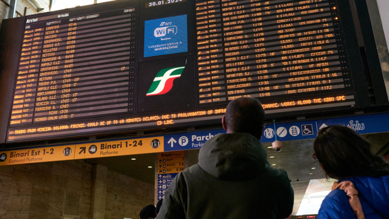 People look at a giant board with the logo of Trenitalia displaying the time table of the trains at Termini railway station in Rome, on January 30, 2024. Trenitalia is a subsidiary of Ferrovie dello Stato Italiane the primary train operator in Italy. Meloni's hard-right government aims to raise 20 billion euros ($21.6 billion) by 2026 by selling off a stake in Poste Italiane, which turns big profits through its insurance and banking operations, as well as stakes in rail company Ferrovie dello Stato and energy giant Eni. (Photo by Andreas SOLARO / AFP) (Photo by ANDREAS SOLARO/AFP via Getty Images)