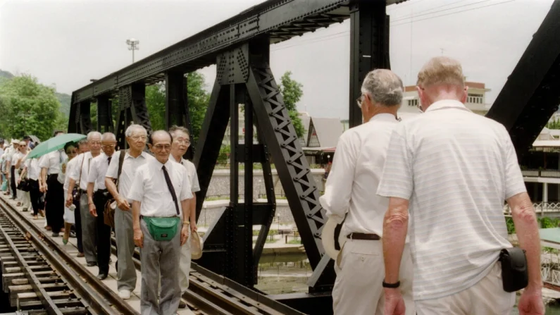 In occasione del 50° anniversario della fine della Seconda Guerra Mondiale, veterani giapponesi (guidati da Nagase Takashi) marciano attraverso il tratto più famoso della Ferrovia Birmana, il ponte sul fiume Kwai, per incontrare due ex prigionieri di guerra australiani il 15 agosto 1995 a Kanchanaburi, in Thailandia. KULTIDA PIRIYPHAN/Getty Images